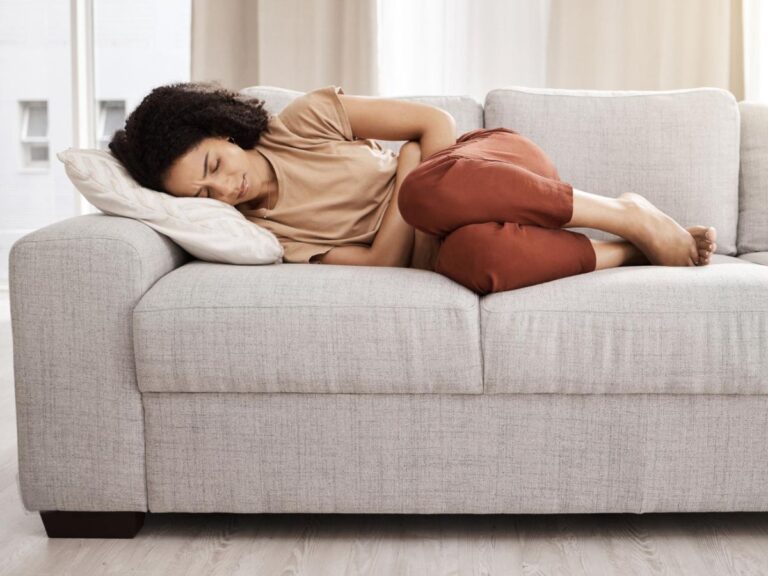 woman laying on a couch appears to be in pain